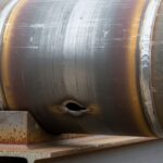 Heavy duty carbon steel pipe wear pad welded to process piping on structural steel support shoe