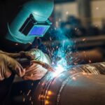 A welder performing a critical golden joint weld on an industrial steel pipeline.