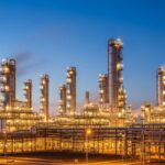 Modern petroleum refinery plant with illuminated distillation towers at dusk.