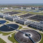 Aerial view of a modern municipal wastewater treatment plant featuring circular clarifiers and aeration basins.