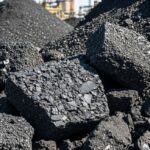 Raw black petroleum coke piles at an industrial refinery yard