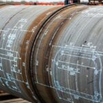 Industrial steel pipeline with engineering blueprint overlay showing wall thickness calculations.