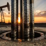 Steel sucker rod string being installed at an oil well pumpjack site.