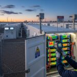 A professional technician performing thermal inspection on a utility-scale BESS plant battery rack to ensure operational safety and efficiency.