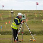 Professional surveyor using a Total Station on a large data centre construction site for topographical mapping.