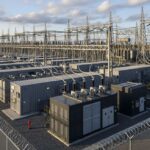 Utility-scale Battery Energy Storage Systems facility connected to a high-voltage electrical substation for grid stabilization.