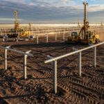 Construction site showing ground improvement techniques applied to a large-scale solar energy project with steel pile foundations.