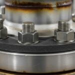 Industrial flange connection with high-strength alloy steel studs and nuts in a refinery piping system.