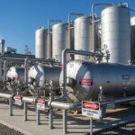 Modern industrial hydrogen storage facility with stainless steel tanks and safety piping.