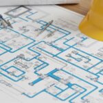 Detailed piping isometric drawing on an engineer's desk showing various piping abbreviations and symbols.