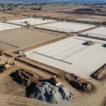 Aerial view of utility-scale solar farm construction site showing earthwork grading and cut-and-fill operations for tracker installation.