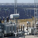 Utility-scale solar power plant connected to a high-voltage electrical grid substation.
