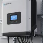 Modern industrial solar inverter unit mounted on a wall with visible cooling fins and electrical conduit connections for PV system energy conversion.