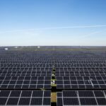 Utility-scale solar farm installation featuring rows of high-efficiency monocrystalline solar panels under a clear blue sky.
