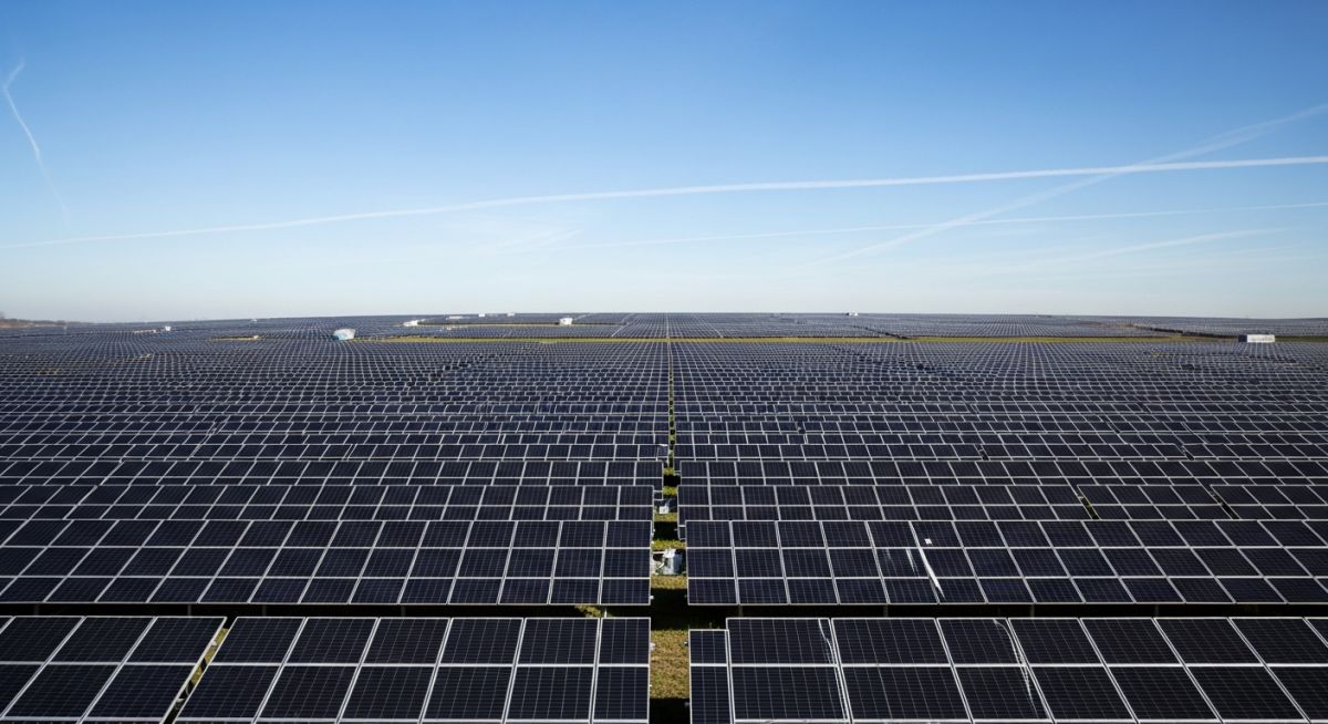 Utility-scale solar farm installation featuring rows of high-efficiency monocrystalline solar panels under a clear blue sky.