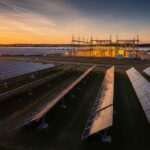 Utility-scale solar power plant with rows of photovoltaic panels under a clear sky, representing large-scale renewable energy investment.