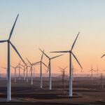 Utility-scale wind farm featuring multiple horizontal axis wind turbines under a clear morning sky, showcasing structural engineering and site layout.